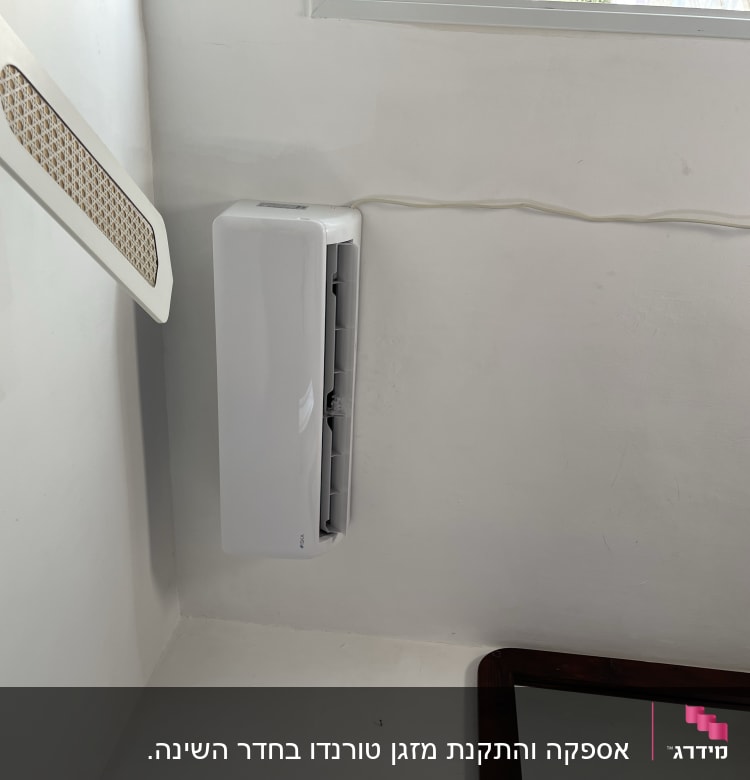מזגן מותקן על קיר לבן עם כבל חשמל